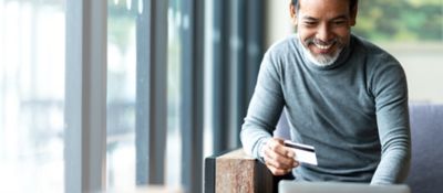 Man purchasing item from laptop using credit card, Cloud Platforms | DXC Technology Insights